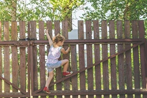 The small kid playing with wooden fence wall